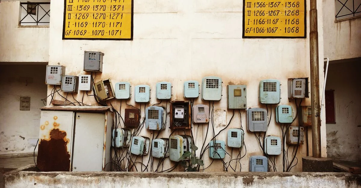 Compteurs électriques anciens et câblage montés sur un mur en béton d'un vieux bâtiment en Inde.