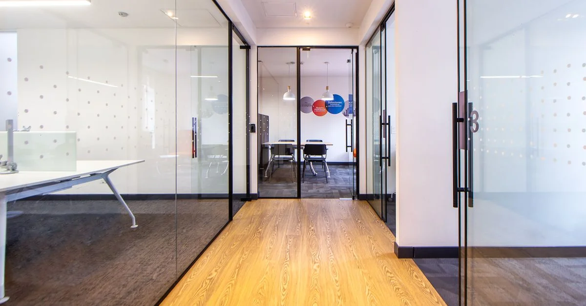 Couloir de bureau moderne et lumineux avec des murs en verre menant à une salle de conférence.