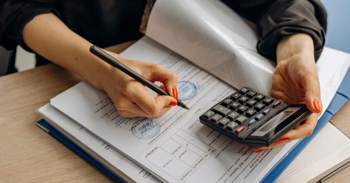 Un contador utilizando una calculadora y firmando papeles, demostrando análisis financiero.