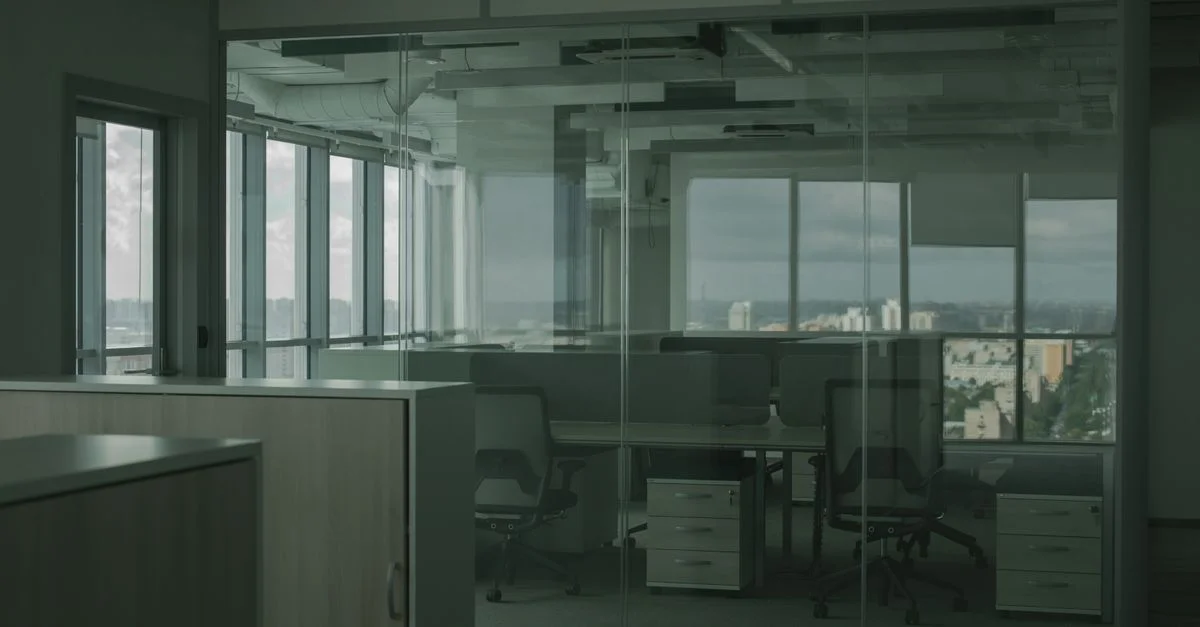 Bureau spacieux et vide avec des murs en verre et une vue sur la ville, idéal pour des environnements de travail modernes.