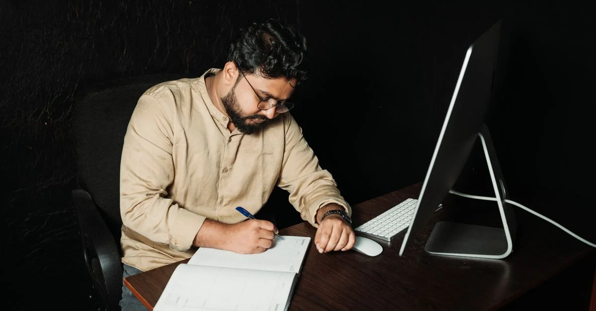 Hombre escribiendo en la oficina con computadora. Trabajo nocturno enfocado en la creatividad y la productividad.