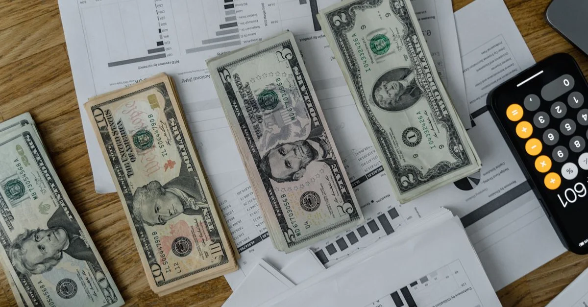 Un espacio de trabajo que presenta dinero, documentos y una calculadora simbolizando análisis financiero y presupuestos.