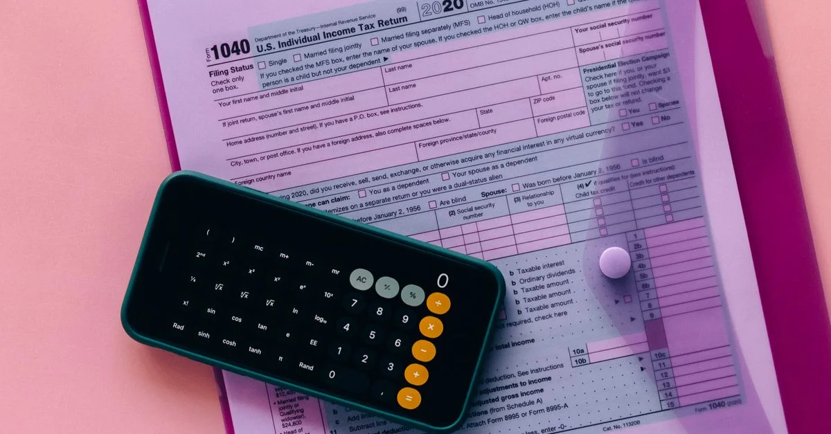 Formulario de impuestos 1040 con una calculadora sobre un fondo rosa, destacando temas de finanzas y contabilidad.
