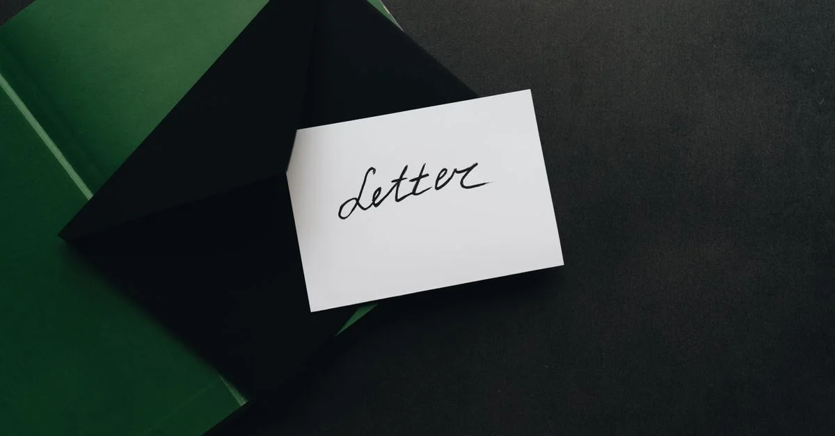 Una disposición plana que muestra un sobre negro con una carta en caligrafía, ofreciendo amplio espacio para texto sobre un fondo oscuro.