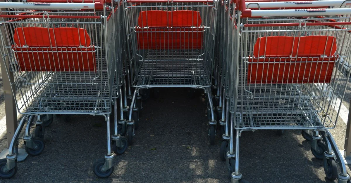 Carritos de compras dispuestos ordenadamente en un estacionamiento al aire libre.