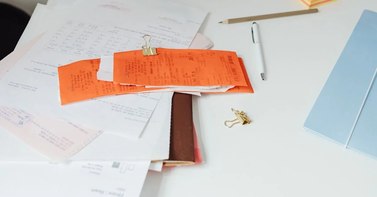 Primer plano de un escritorio ordenado con recibos, documentos y material de oficina para la organización empresarial.