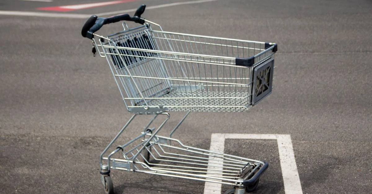 Un carrito de compras solitario está parado en un estacionamiento vacío en un día soleado.