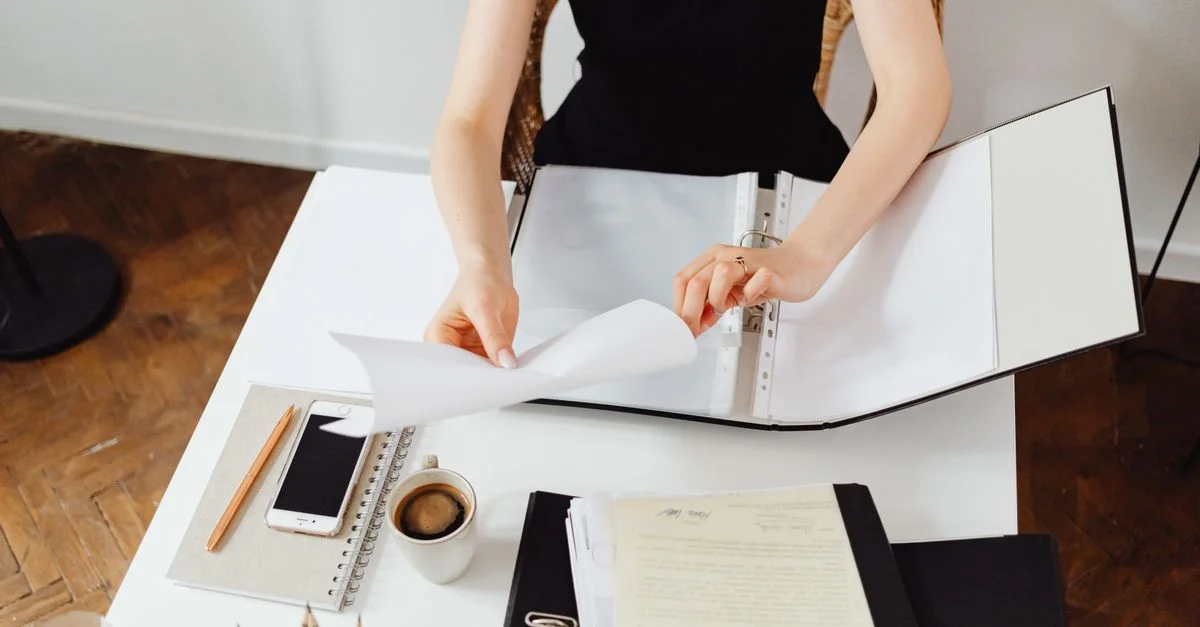 Professionnel travaillant avec des documents à un bureau avec du café et un smartphone.