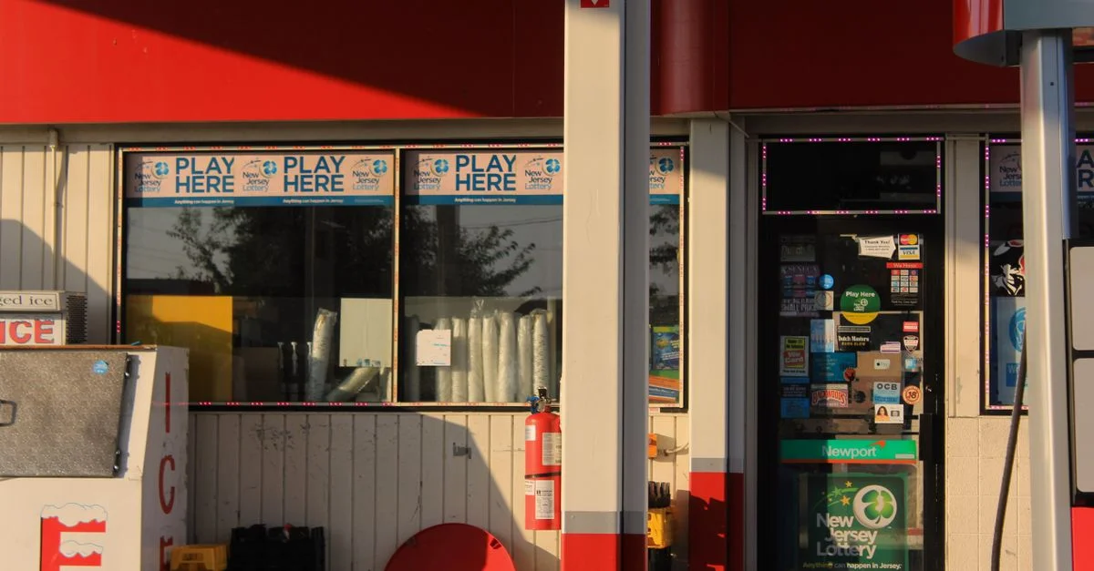 Entrada de la tienda de conveniencia en una gasolinera con carteles de lotería en Bridgeton, Nueva Jersey.