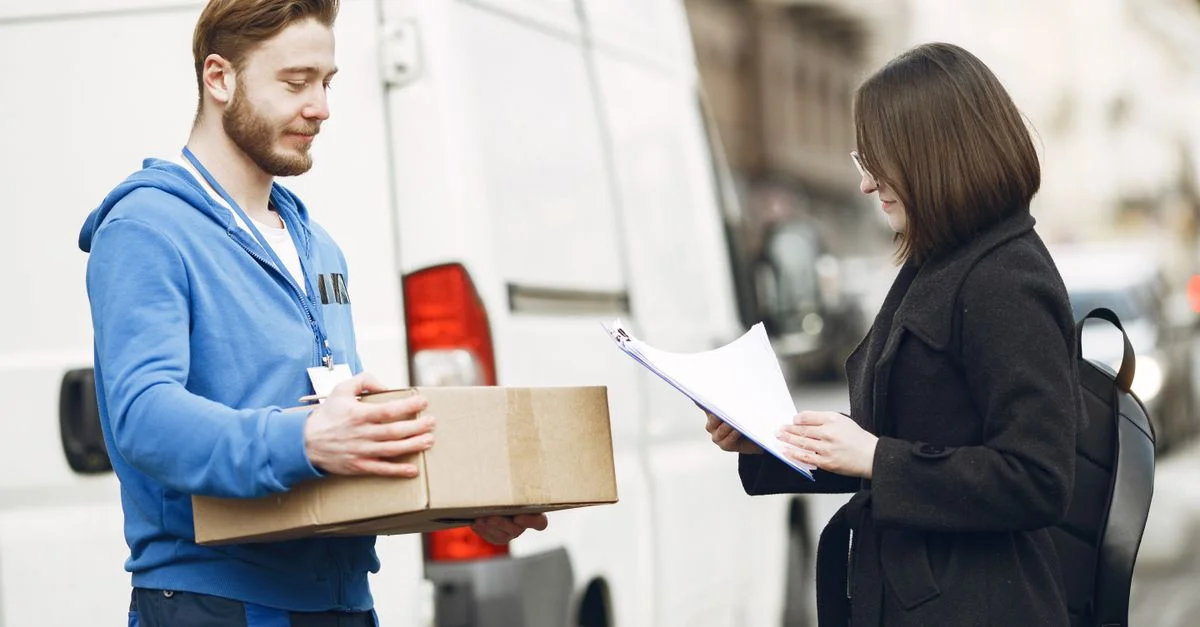 Un mensajero entrega un paquete a una clienta en una calle de la ciudad, facilitando el servicio de entrega.
